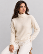 Avery & Mercer AM-US-W02 wearing White - seated / three-quarter soft-knit turtleneck sweater in approved neutral grey studio