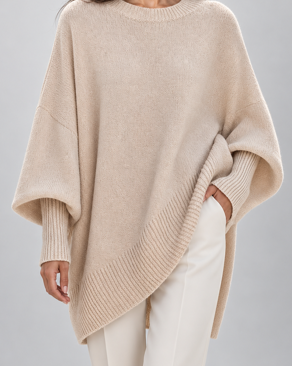 Closer front crop of apricot batwing knit sweater showing crew neck, fine knit, long ribbed cuffs and asymmetric ribbed hem
