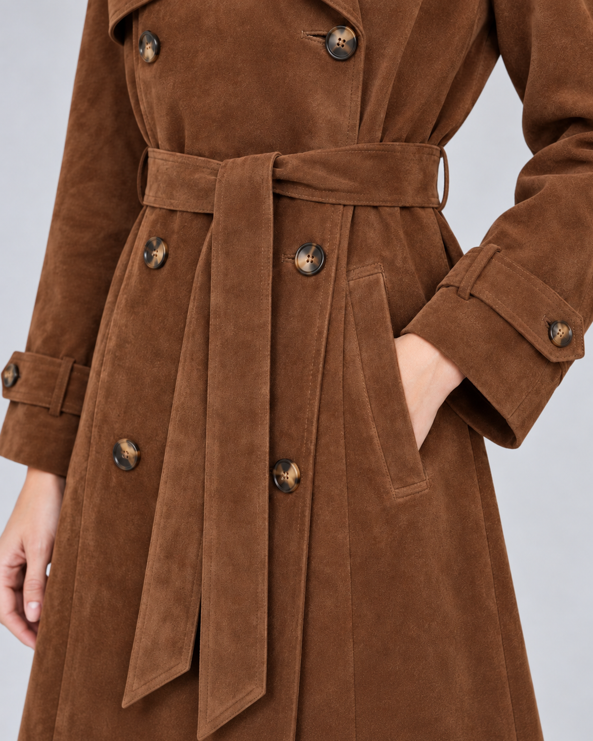 Women's brown suede-effect belted trench coat, belt pocket and cuff detail, photographed in a light grey studio