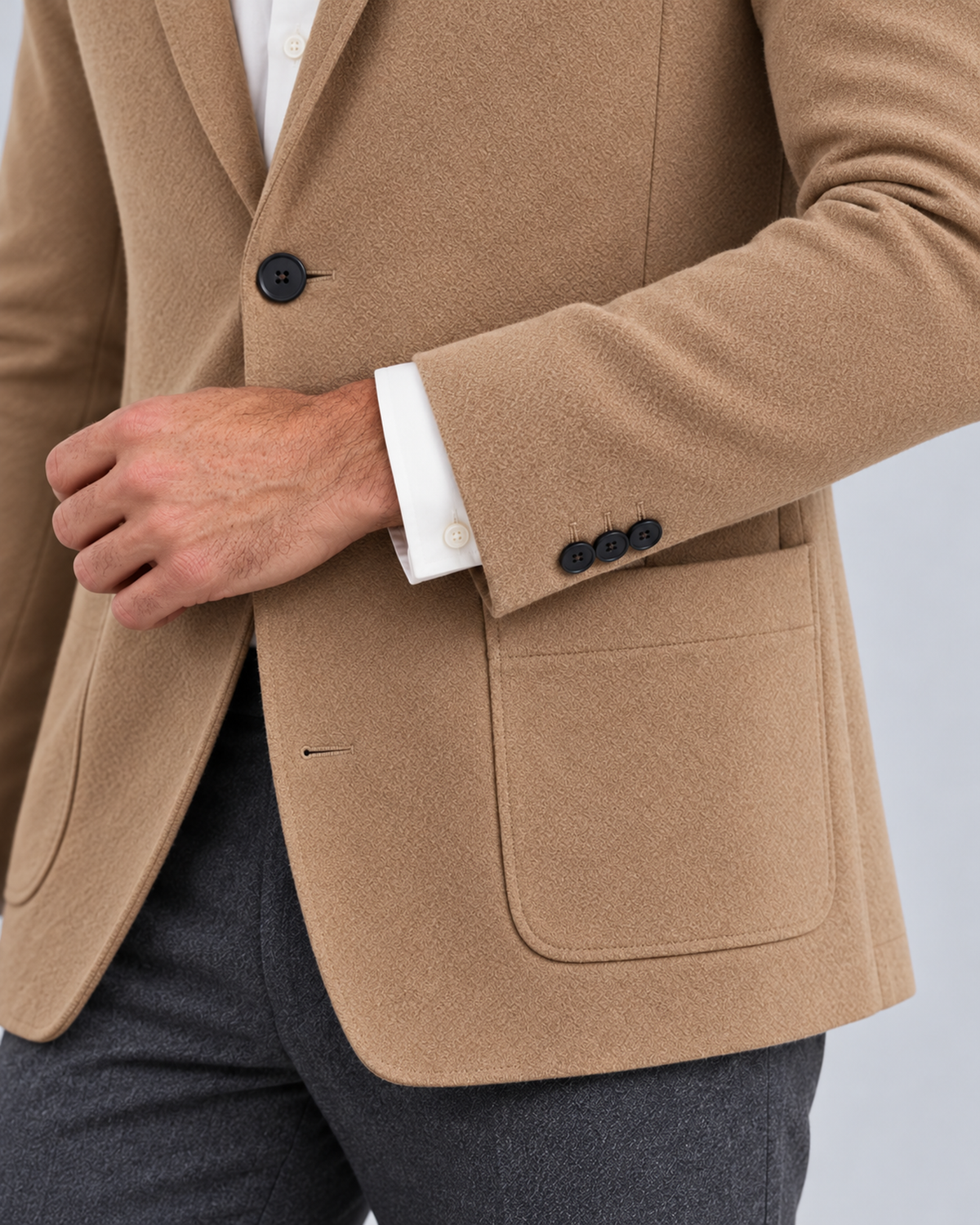 Men's knit blazer jacket in beige, cuff and patch-pocket detail, photographed in a grey studio