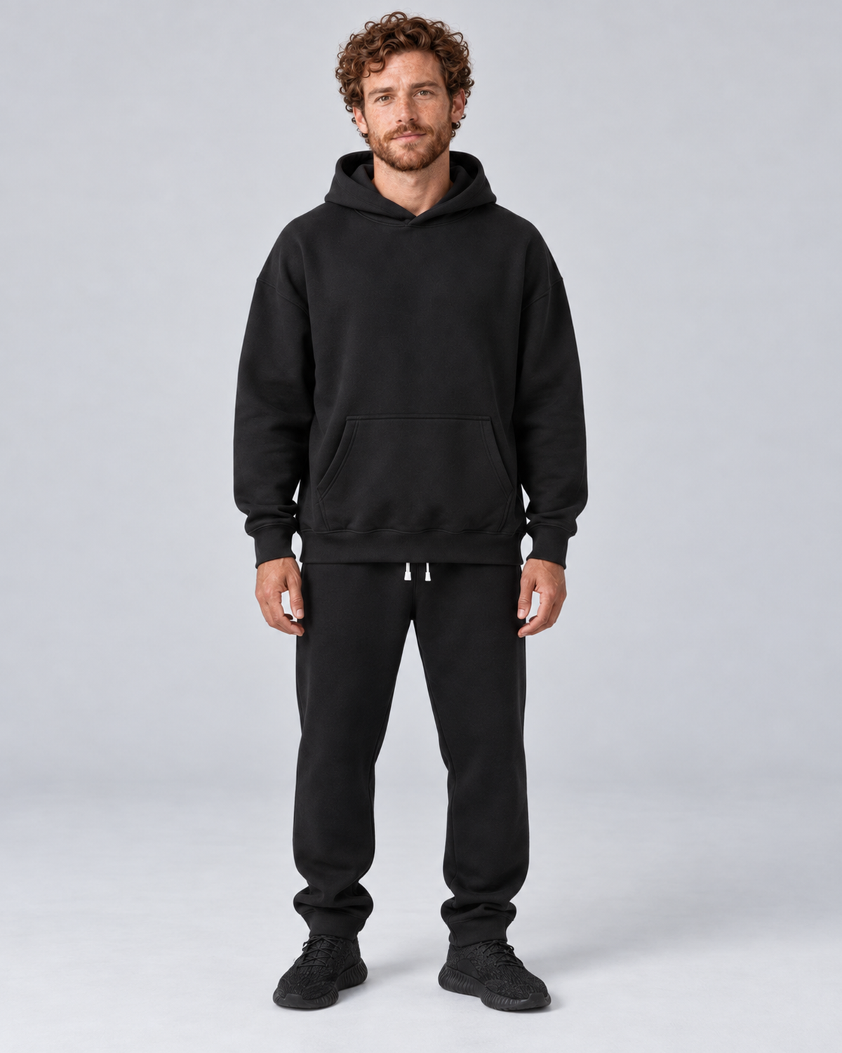 Men's black pullover hoodie and jogger co-ord set, front hero, on approved studio model
