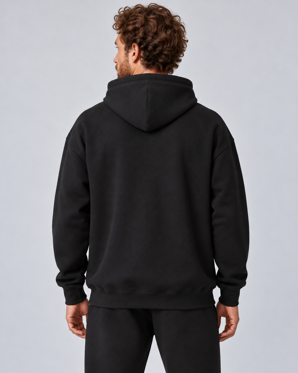 Men's black pullover hoodie and jogger co-ord set, rear hoodie and upper joggers, on approved studio model