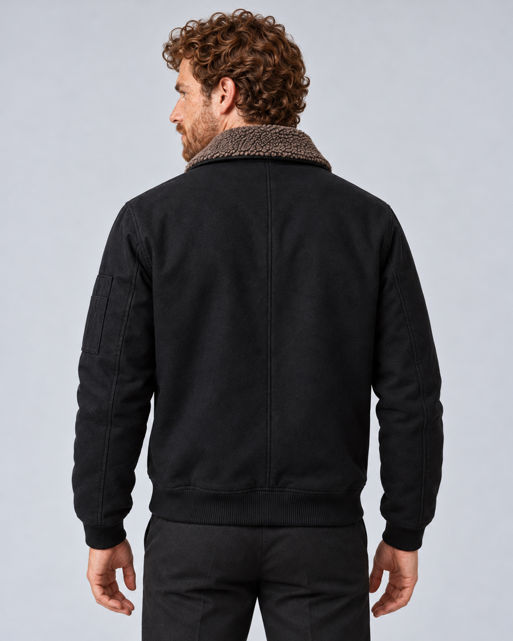 Men’s sherpa-lined zip jacket in black, rear view, photographed against a light grey studio background