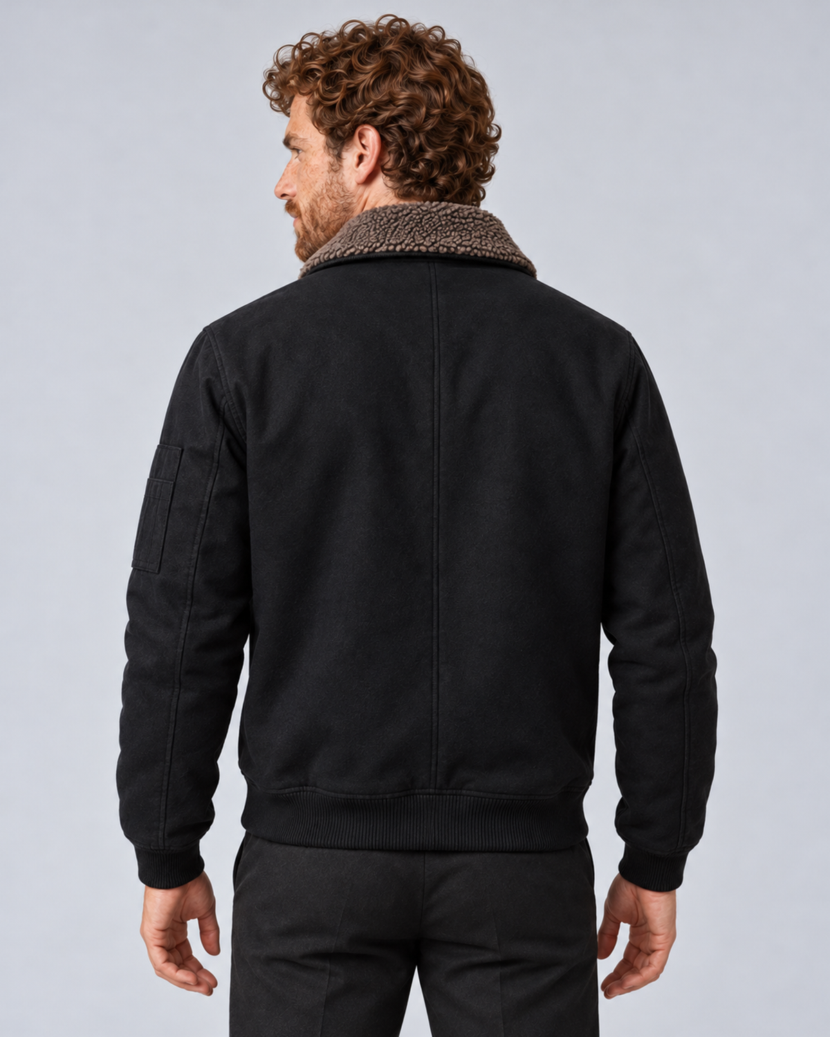 Men’s sherpa-lined zip jacket in black, rear view, photographed against a light grey studio background