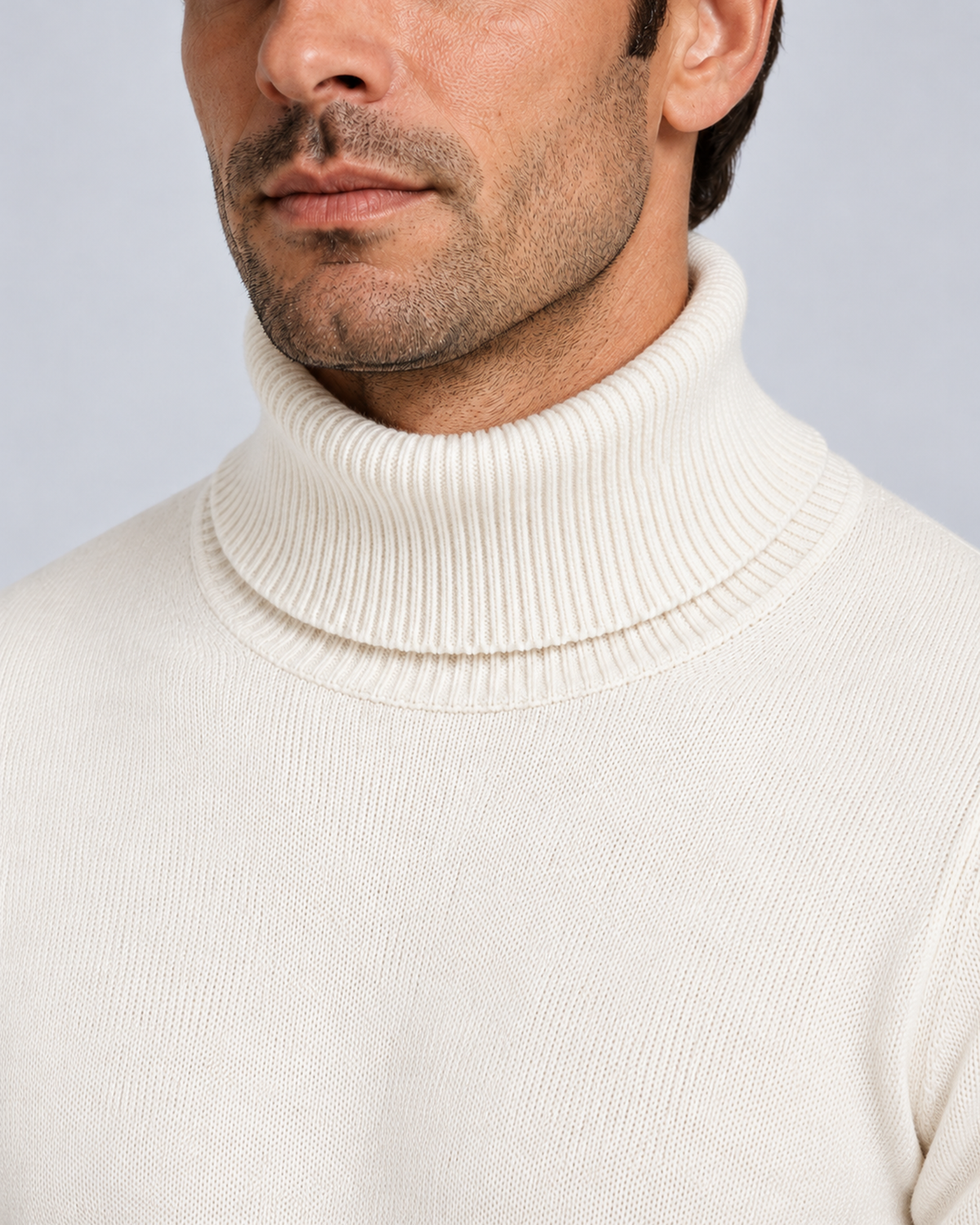 Men's fine-knit turtleneck sweater in white, collar and knit detail, on a male model in a light grey studio