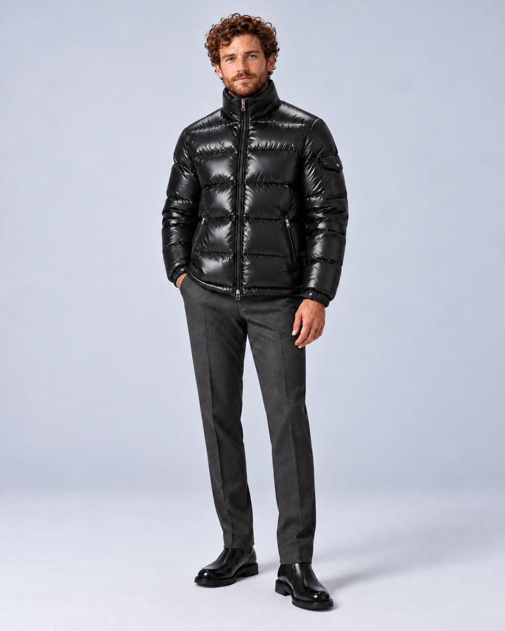 Men's glossy black puffer jacket with removable hood, hood removed fully zipped full-length, on a light grey studio background