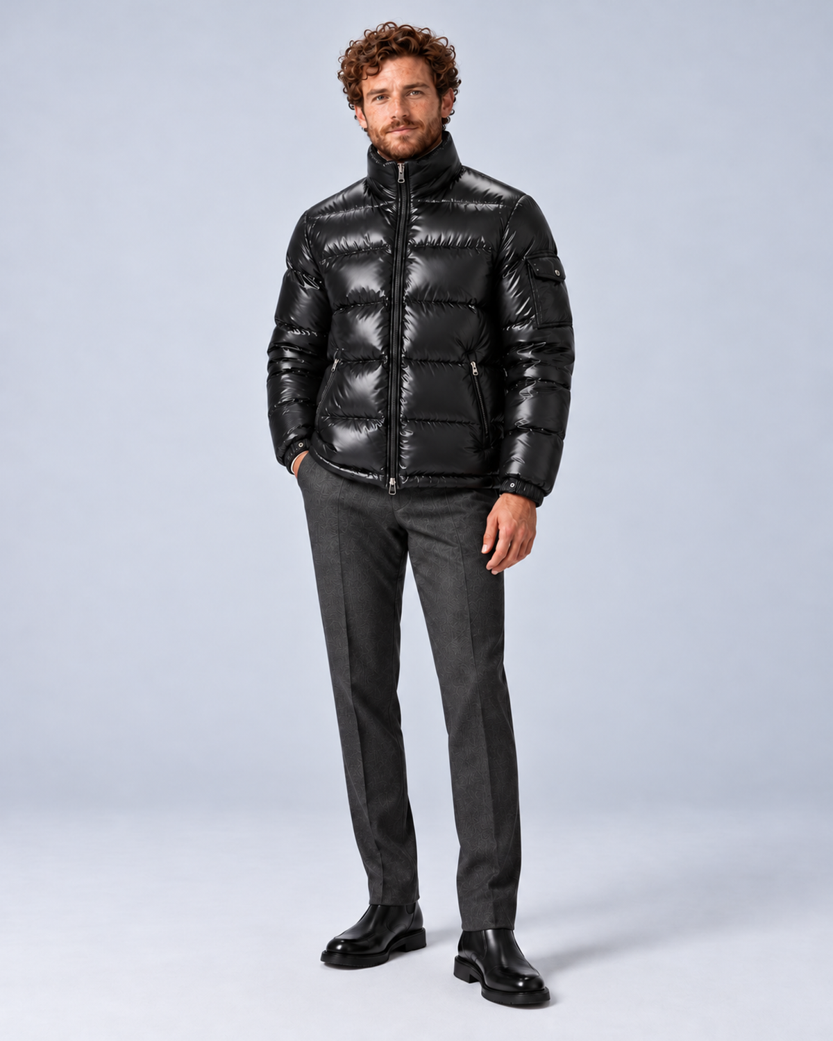 Men's glossy black puffer jacket with removable hood, hood removed fully zipped full-length, on a light grey studio background