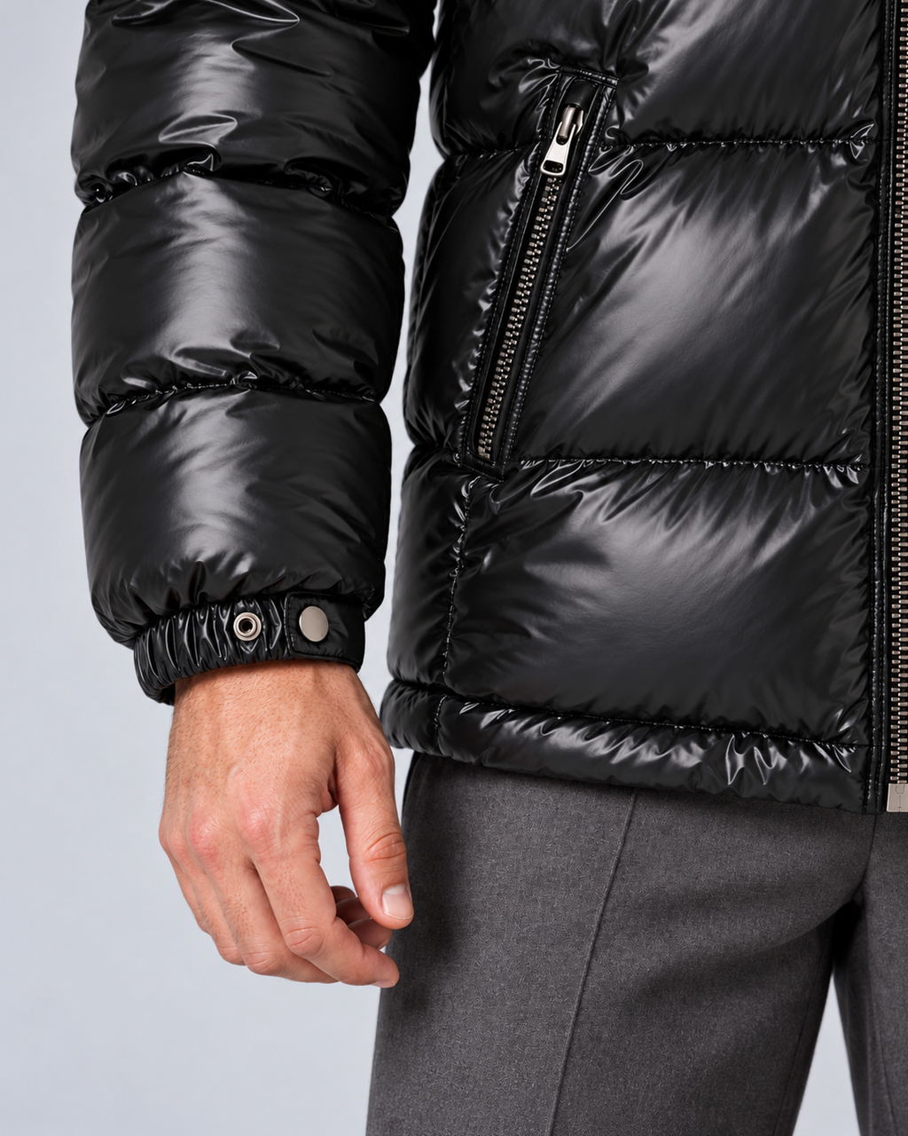 Men's glossy black puffer jacket with removable hood, hip pocket cuff and hem detail, on a light grey studio background