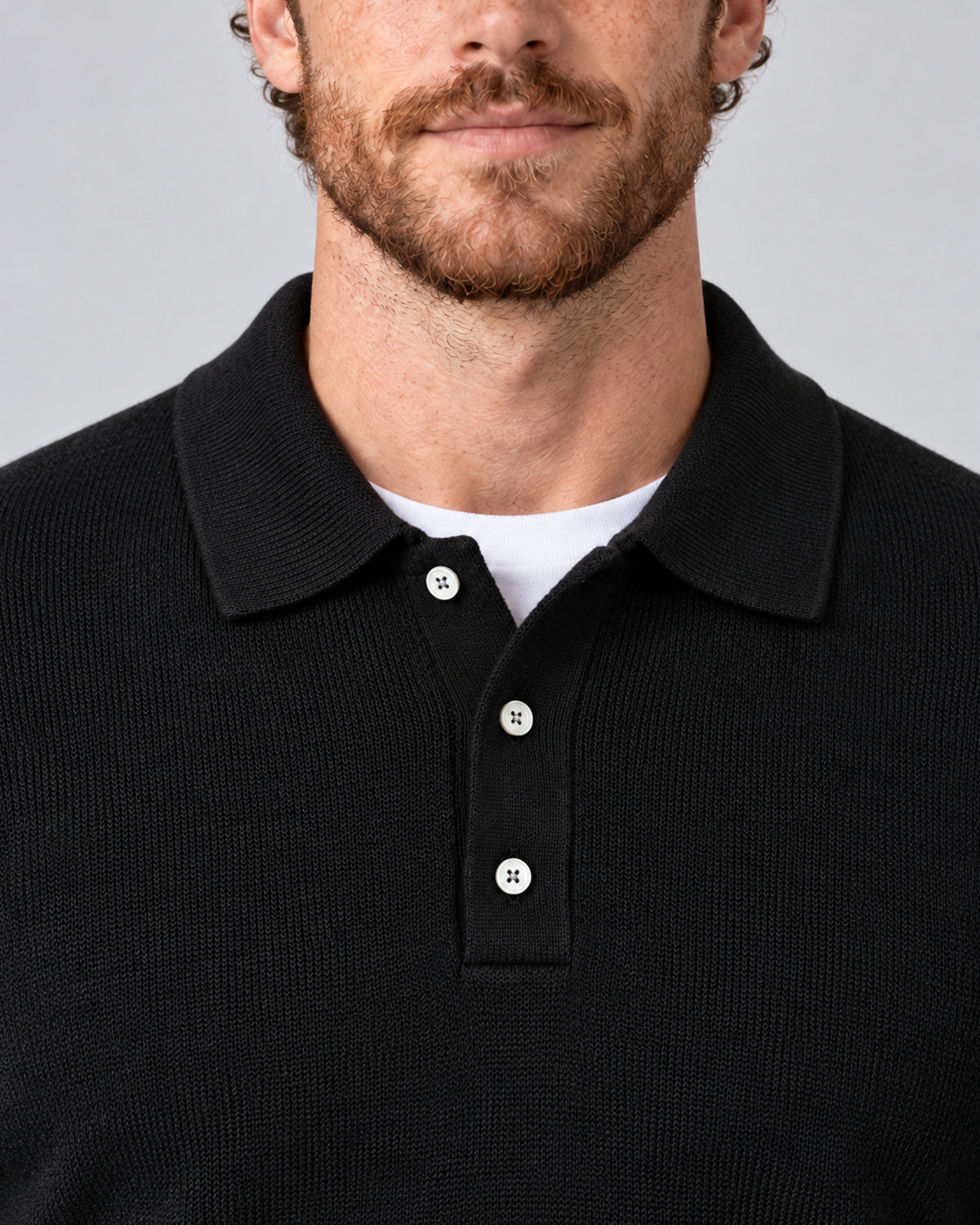 Men’s black textured long-sleeve polo sweater, close-up of collar and three-button placket.