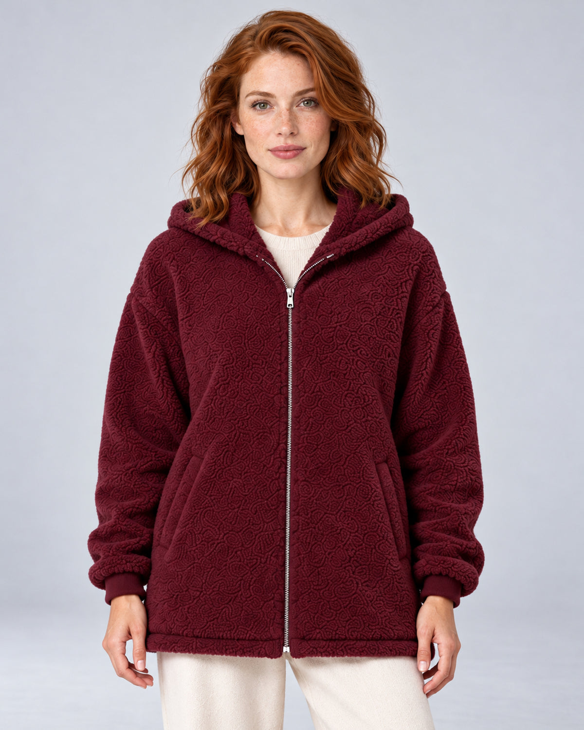 Women's burgundy hooded teddy fleece zip-up cardigan, front view on model.
