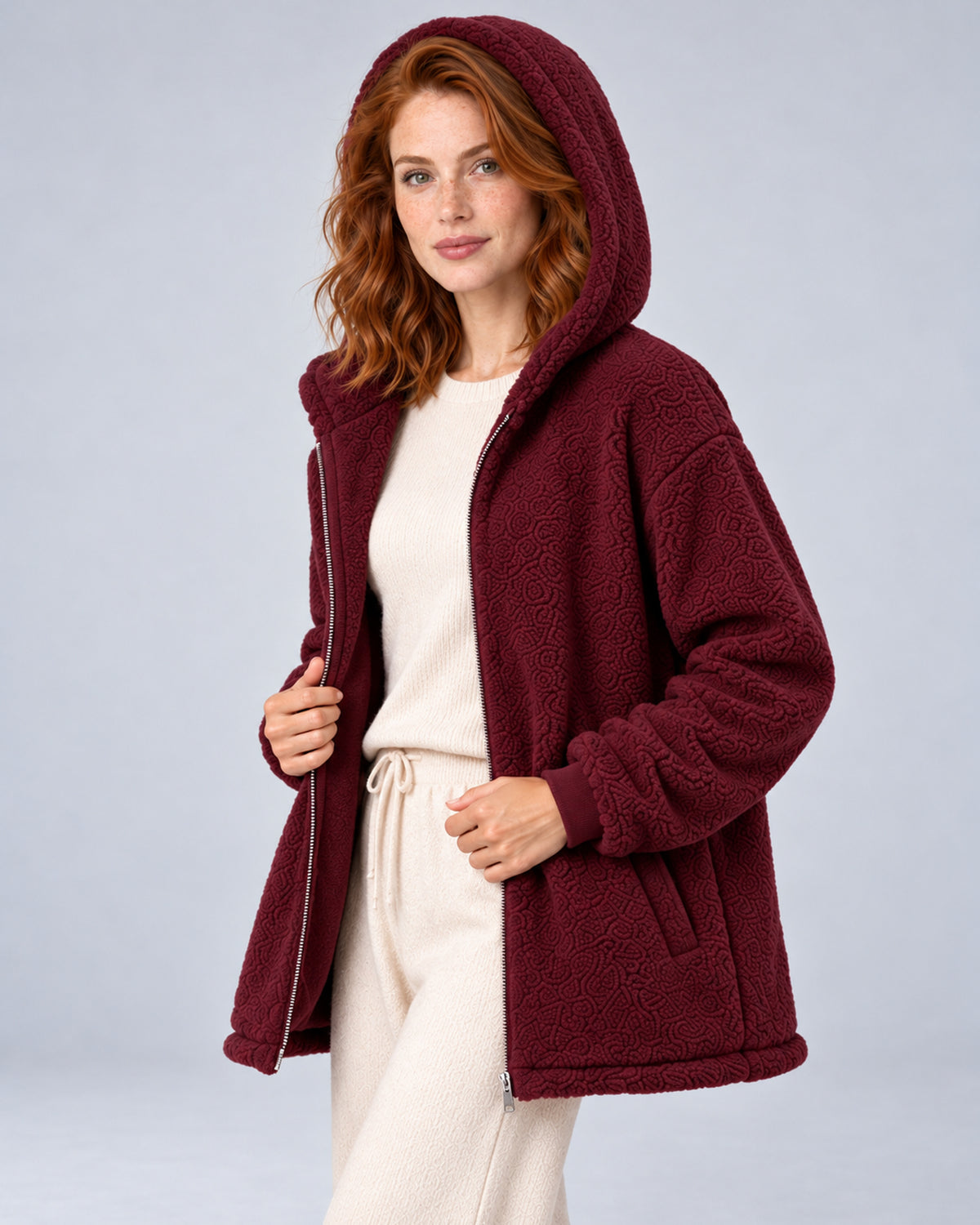 Women's burgundy hooded teddy fleece zip-up cardigan, hood-up three-quarter on model.