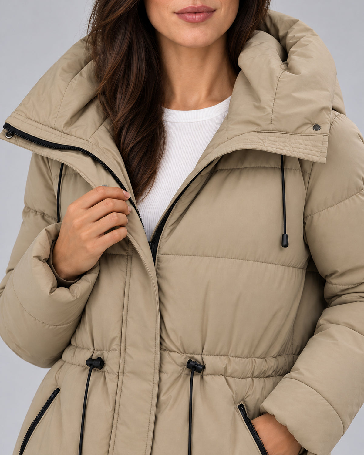 Close-up of the khaki padded parka’s hood, zipper, waist toggles and matte fabric.