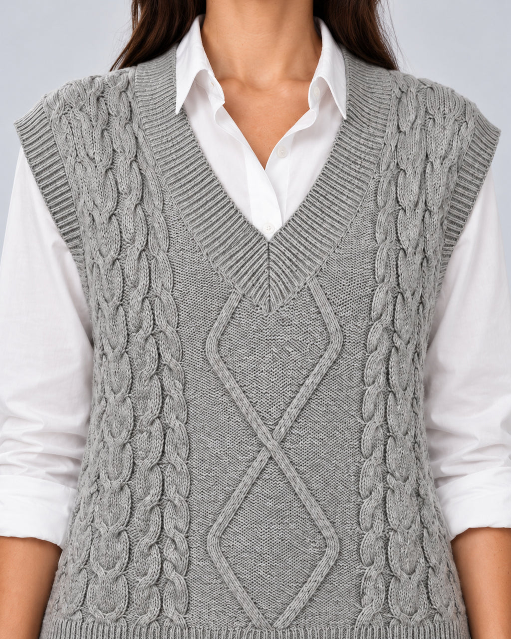 Grey sweater vest close-up showing the ribbed V-neck, diamond cables and textured knit