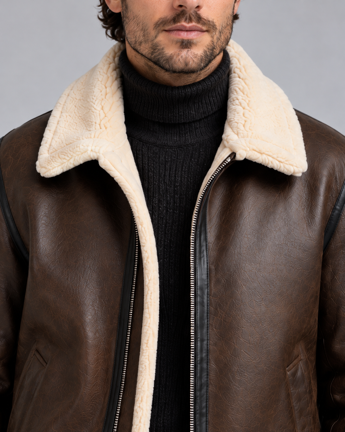 Close-up of the brown aviator jacket showing the cream faux shearling collar, open silver zipper and leather-look texture.