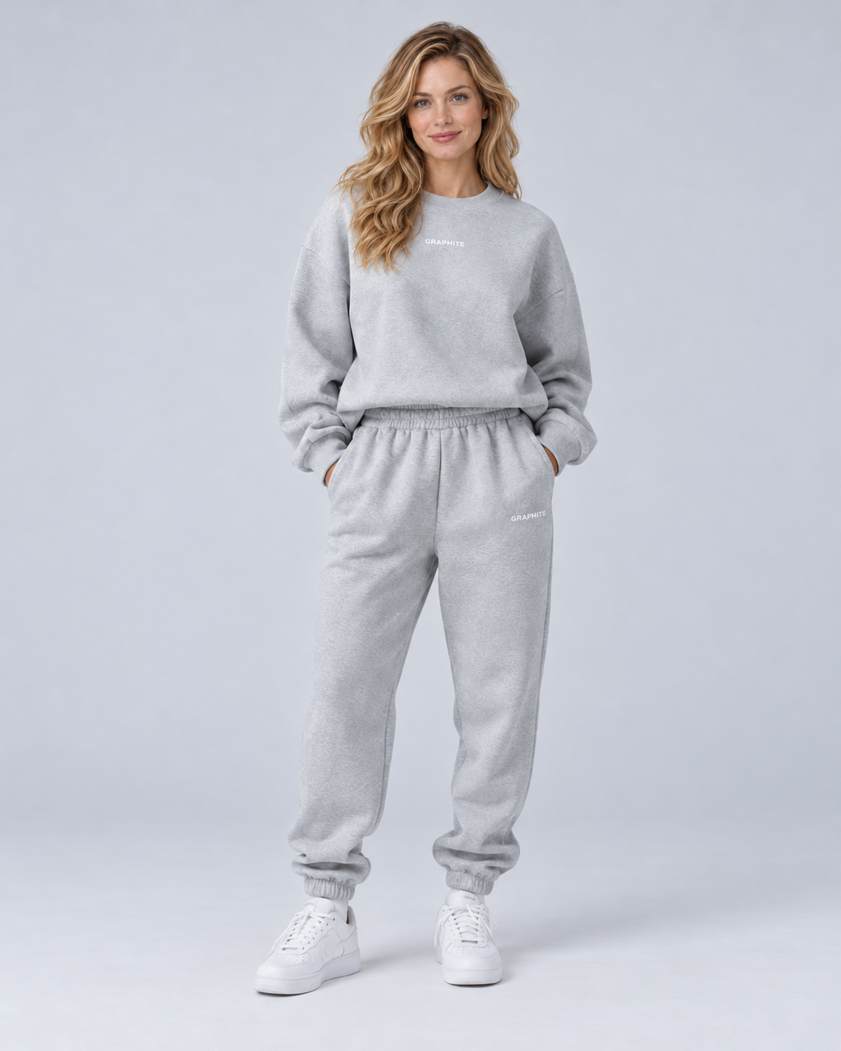 Front view of a grey crewneck sweatshirt and cuffed joggers set with small embroidered lettering.