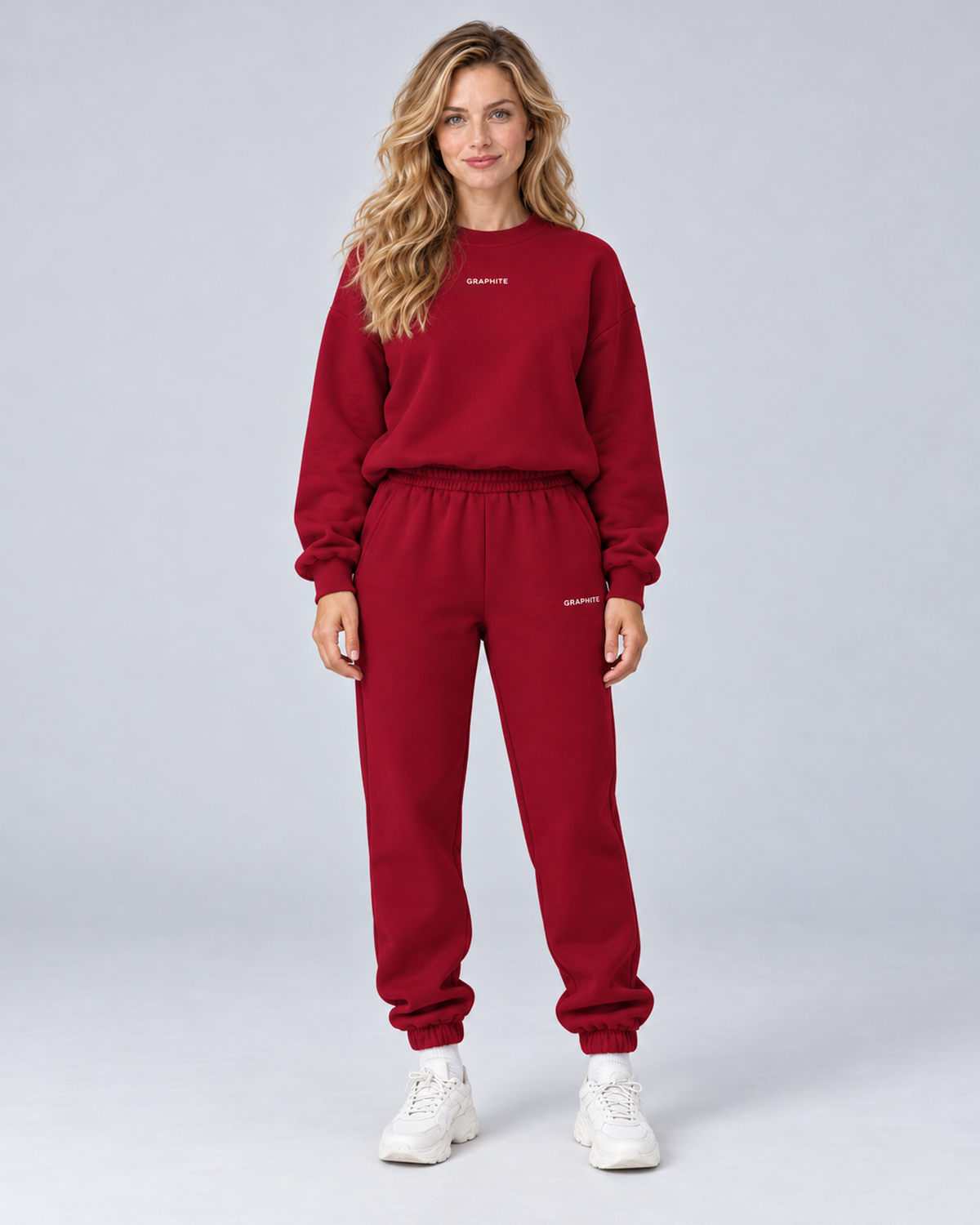 Front view of a burgundy crewneck sweatshirt and cuffed joggers set with small embroidered lettering.
