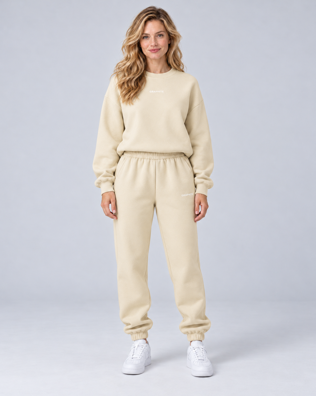 Front view of a apricot crewneck sweatshirt and cuffed joggers set with small embroidered lettering.