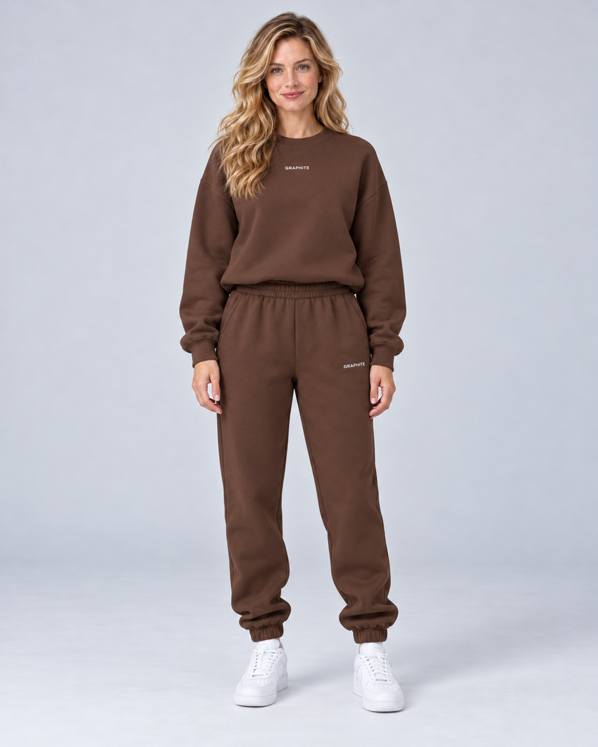 Front view of a chocolate crewneck sweatshirt and cuffed joggers set with small embroidered lettering.