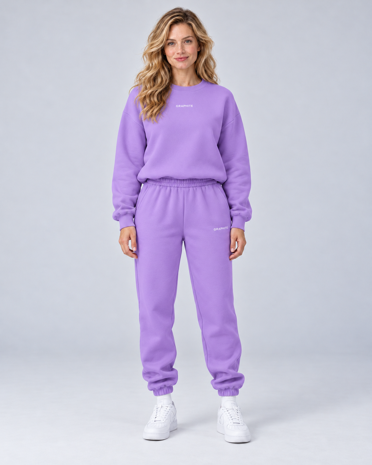 Front view of a purple crewneck sweatshirt and cuffed joggers set with small embroidered lettering.