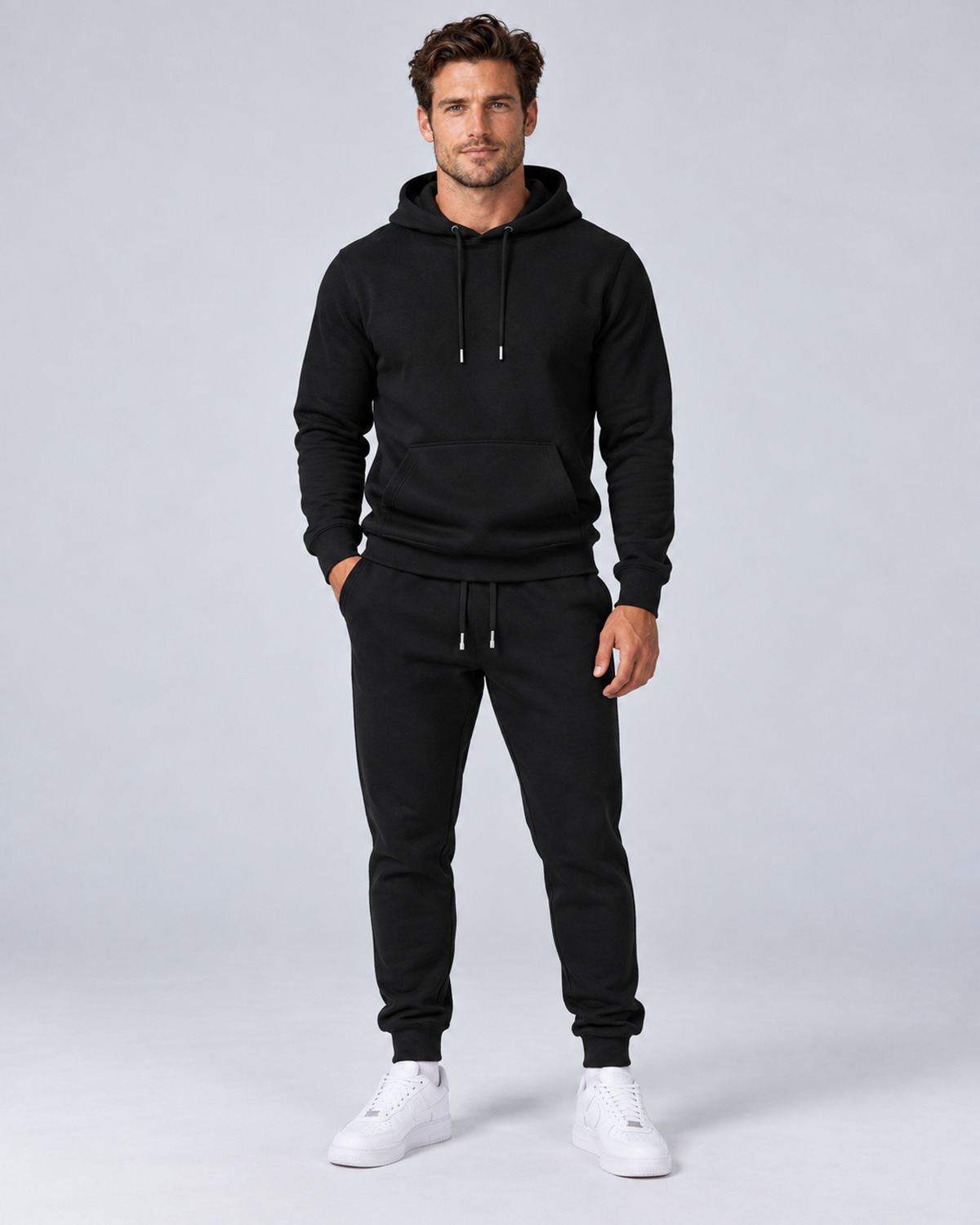 Men's pullover hoodie and cuffed jogger set in black, front hero, on approved studio model