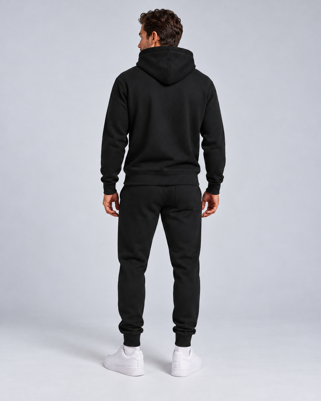 Men's pullover hoodie and cuffed jogger set in black, rear full-length, on approved studio model