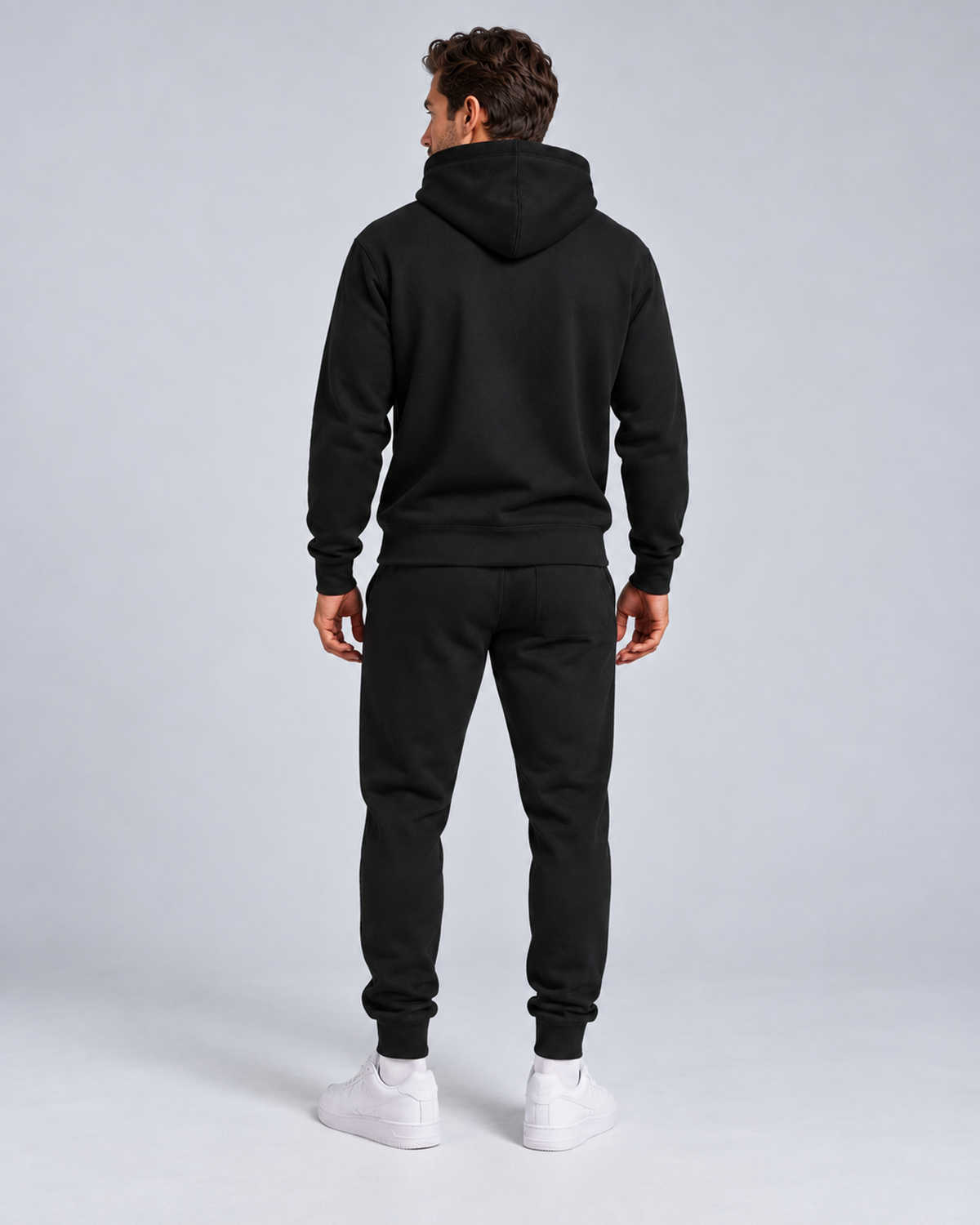 Men's pullover hoodie and cuffed jogger set in black, rear full-length, on approved studio model