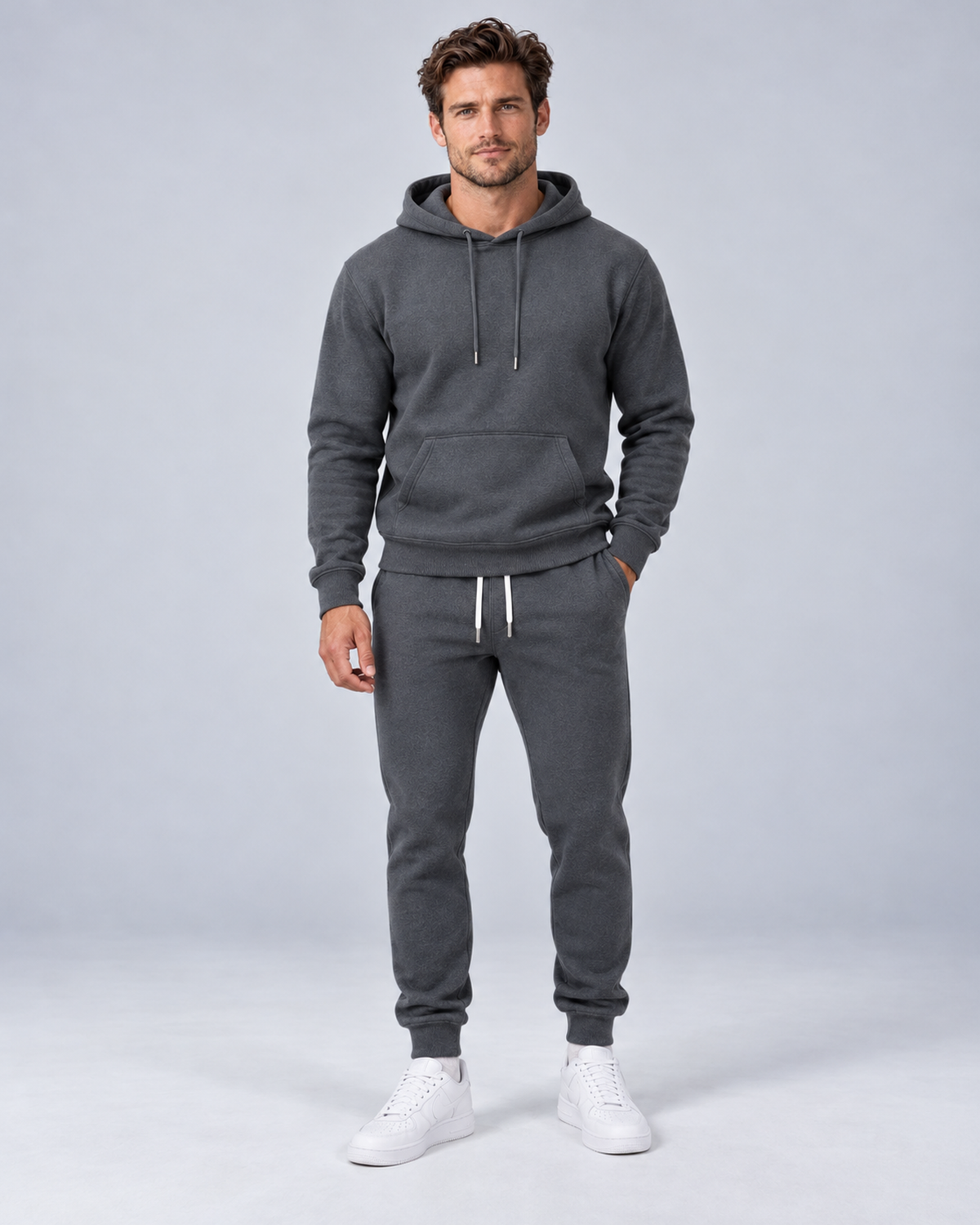 Men's pullover hoodie and cuffed jogger set in dark grey, front hero, on approved studio model