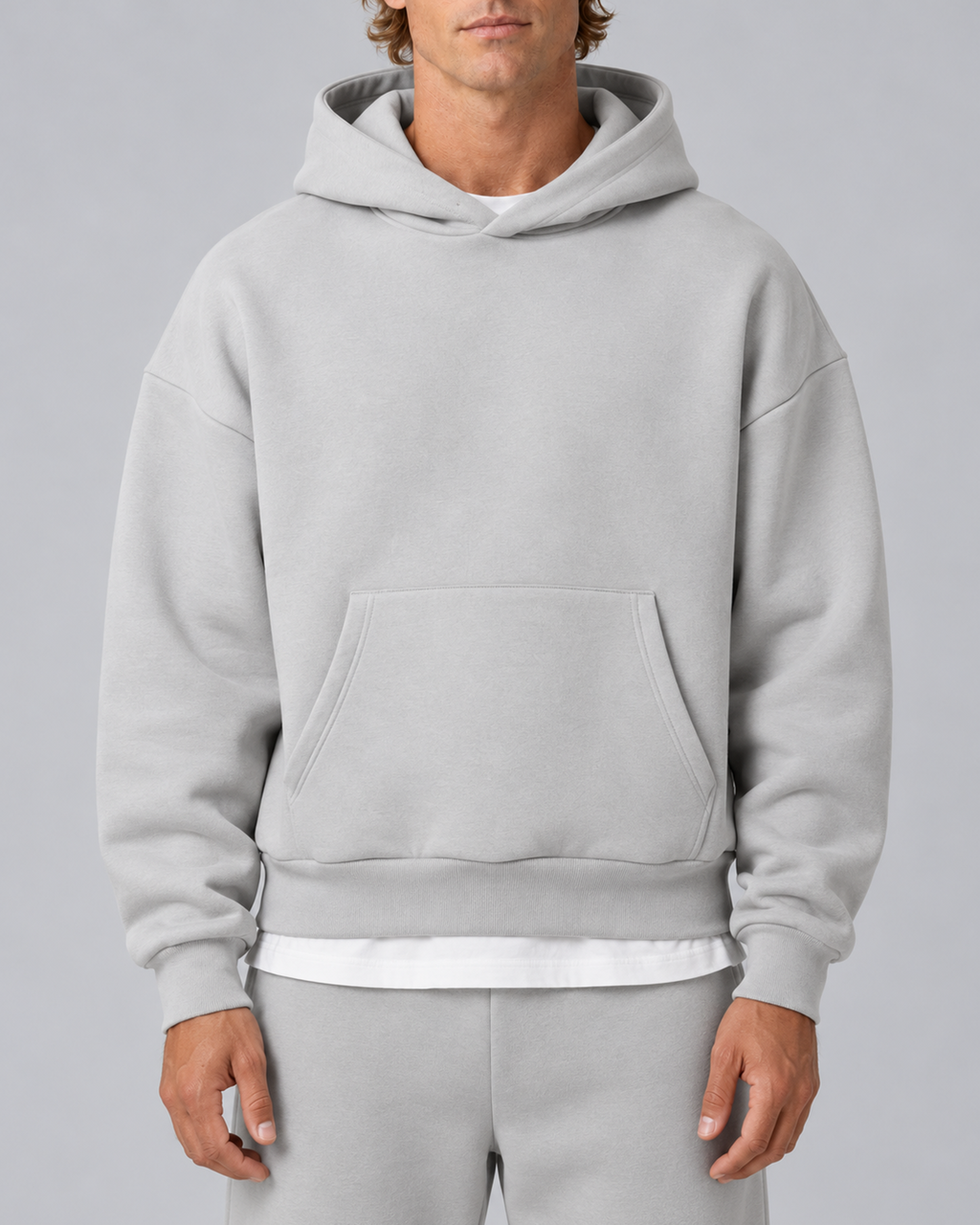 Men's pullover hoodie and straight-leg tracksuit set in light grey, hoodie construction detail, on approved studio model
