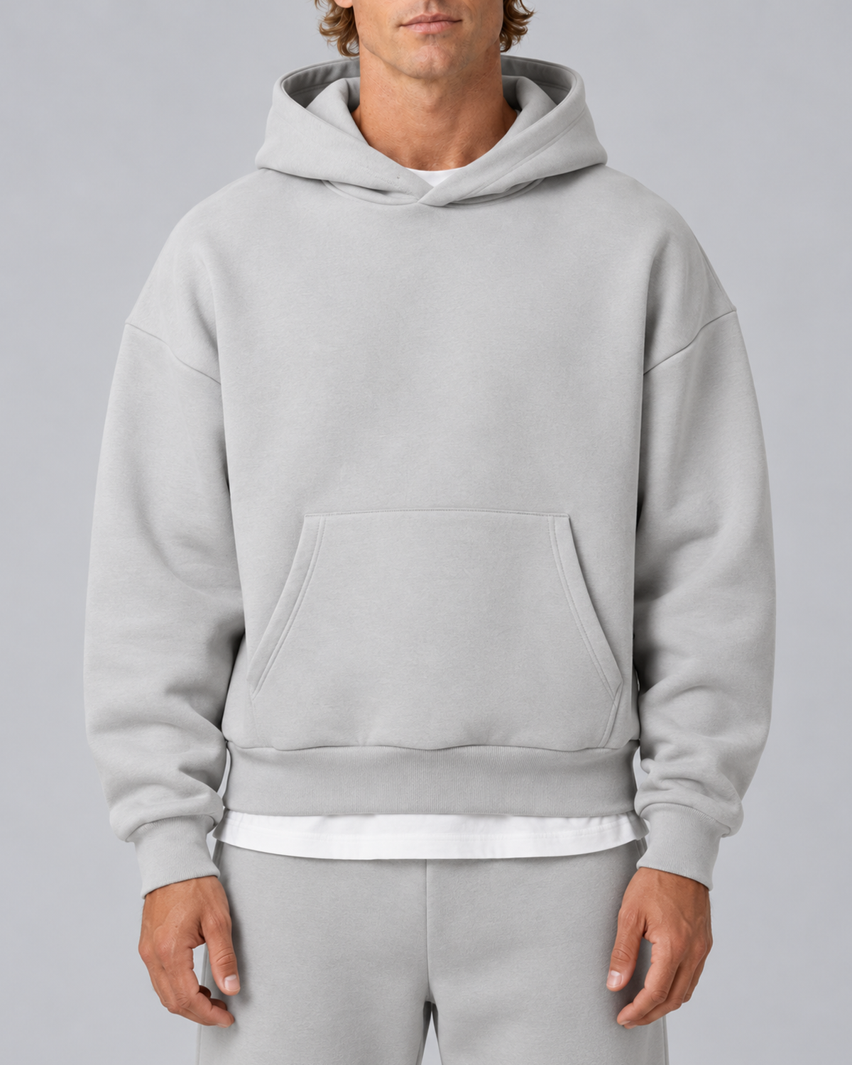 Men's pullover hoodie and straight-leg tracksuit set in light grey, hoodie construction detail, on approved studio model
