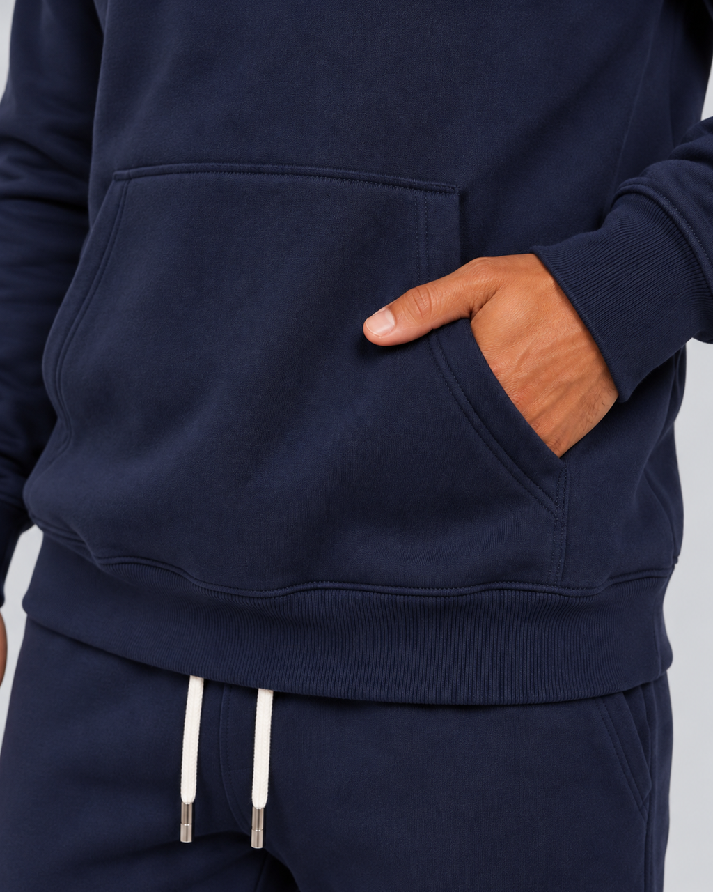 Men's pullover hoodie and cuffed jogger set in navy, kangaroo pocket detail, on approved studio model